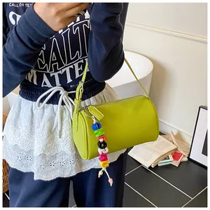 Dettaglio borsa a cilindro in pelle verde con ciondolo decorativo di perline colorate