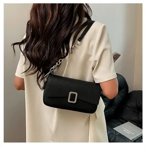 Detail of black pebbled leather handbag with silver lock and chain strap on shoulder