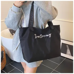 Close-up of black oversized tote bag with white I'm Creamy embroidery text