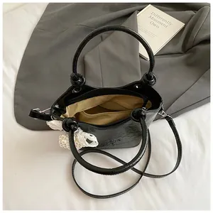 Schicke schwarze Beuteltasche mit Krokoprägung und Perlen-Schleife für den Sommer-Look