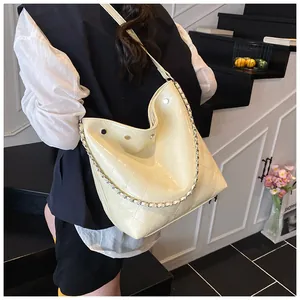 Detail of beige quilted bucket bag with chain strap and rivets shown on a model