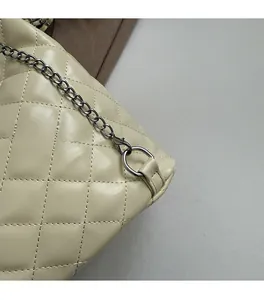 Macro detail of beige quilted leather texture and premium gunmetal chain on handbag