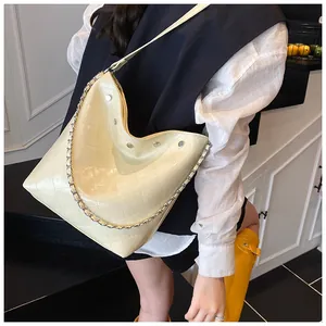 Detail of cream quilted chain hobo bag with glossy finish and silver stud accents