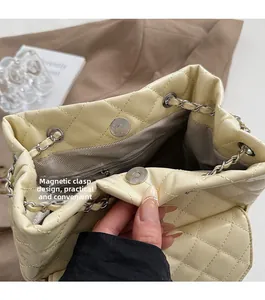 Detail of magnetic buckle closure and quilted interior of cream crossbody bag