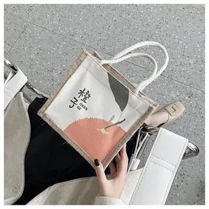 Detail of canvas tote bag featuring orange print design and sturdy cotton rope handles