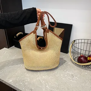 Large beige woven straw tote bag with brown leather handles and adjustable shoulder strap