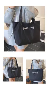 Detail of black canvas tote bag with I am Creamy embroidery and ruffled wave handles