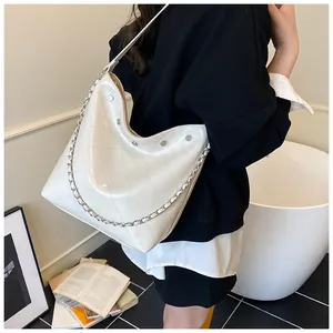 Detailed close-up of cream quilted bucket bag with silver chain and rivet accents