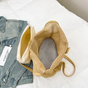 Large hollow woven straw tote bag with yellow leather trim and canvas inner pouch