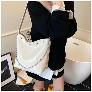 Close-up of creamy white quilted hobo bag with silver studs and chain details in a scene
