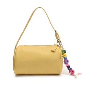 Borsa a secchiello cilindrica in pelle gialla con trama litchi e ciondolo colorato