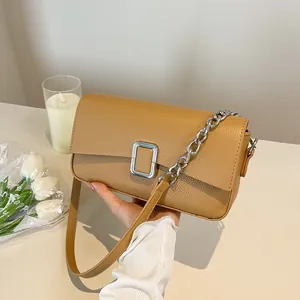 Brown lychee leather shoulder bag with silver chain and metal buckle on table