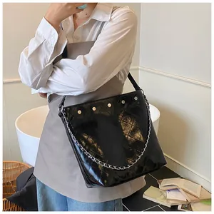 Close-up of black quilted bucket bag with silver studs and chain detail on leather