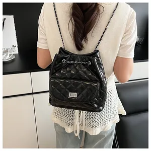 Detail of a black quilted leather backpack with silver metallic lock and chain strap