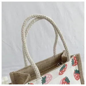 Detailed shot of a jute tote bag featuring strawberry prints and braided rope handles