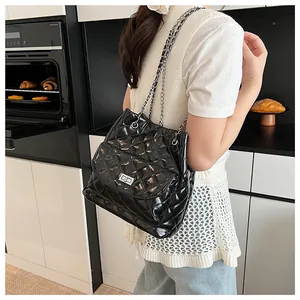 Quilted black glossy leather shoulder bag with silver turn-lock shown on a model
