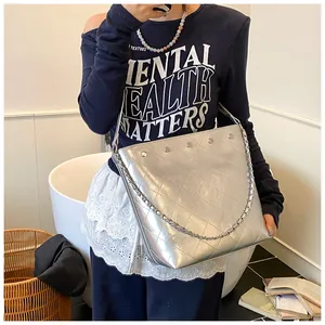 Detail view of silver quilted bucket bag with chain strap and metallic stud accents