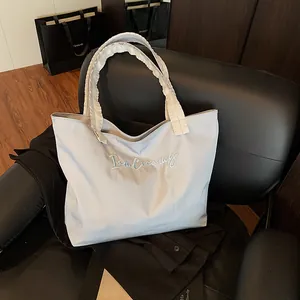 Stylish light blue tote bag with ruffle straps and embroidery on a black seat