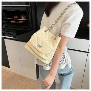 Close-up of beige quilted chain bag with silver twist lock and glossy diamond pattern