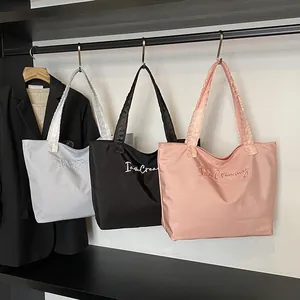 Three satin tote bags in blue, black, and pink with I am Creamy embroidery on a rack