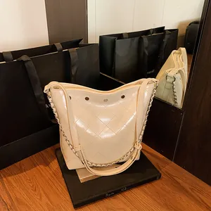 Chic beige quilted bucket bag with leather-chain strap and sleek glossy finish