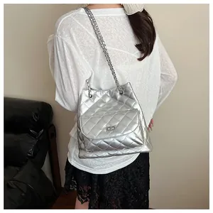 Silver quilted chain bag shown on model with metallic finish and drawstring detail
