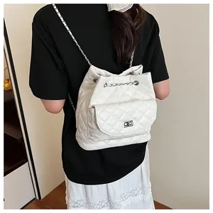 Detail of white quilted leather backpack showing chain straps and drawstring on model