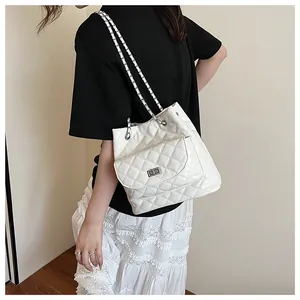 Detail of white quilted bucket bag with chain strap shown on a female model