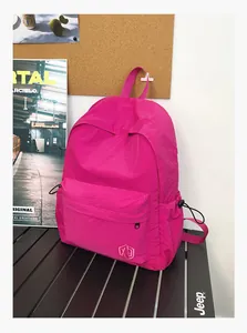 Détail d'un sac à dos magenta avec texture quadrillée, logo brodé et poches latérales