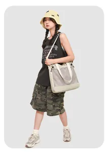Détail du sac cabas en maille beige montrant le cordon et le renfort de la matière