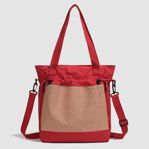 Détail du sac fourre-tout en nylon rouge avec poche en maille kaki et bandoulière réglable