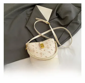 Détail du sac seau crème avec motif d'ours et fermoir rotatif en métal doré élégant