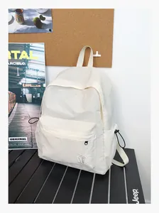 Détail du sac à dos en nylon blanc avec logo géométrique et poches latérales à cordon