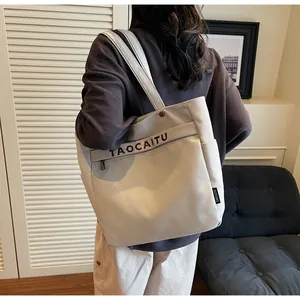 Dettaglio della borsa tote in tela con stampa di lettere e zip in metallo sulla modella