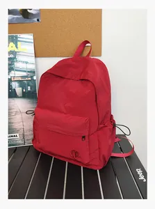 Détail d'un sac à dos rouge avec texture quadrillée et poche latérale à cordon