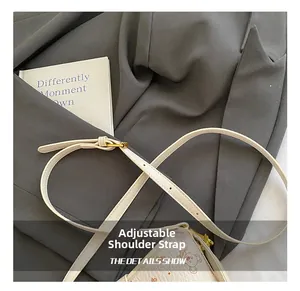 Détail de la bandoulière réglable blanche avec boucle dorée sur un sac seau imprimé ours