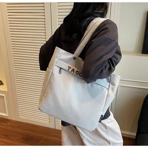 Dettaglio della vista posteriore di una borsa tote in tela beige con cinghie stampate