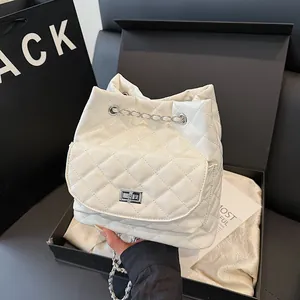 White quilted mini backpack with silver chain and twist lock on black display box