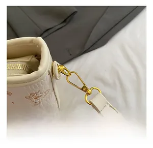 Vue détaillée du sac seau en cuir crème avec imprimé ours et crochet métallique doré