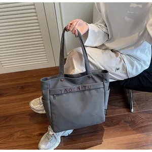 Dettaglio della borsa tote in tela grigia con ricamo e tasche laterali pratiche