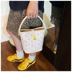 Détail du sac seau blanc avec imprimé ours et fermoir rotatif en métal doré