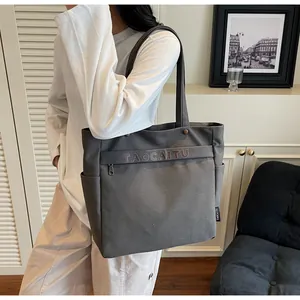 Dettaglio della borsa tote in tela grigio scuro con tracolla indossata da modella