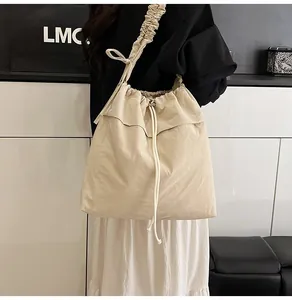 Dettaglio borsa a spalla in nylon crema con tracolla a balze e chiusura a coulisse
