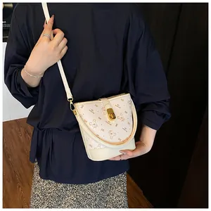 Détail du sac seau en cuir crème avec imprimé ours et fermoir rotatif en métal doré