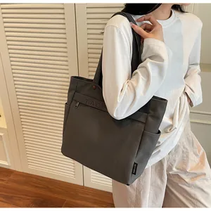 Dettaglio della borsa tote in tela grigio scuro con tasca laterale e stampa di lettere TAOC