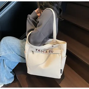 Dettaglio della borsa tote in tela bianco sporco con ricami marroni e tasche