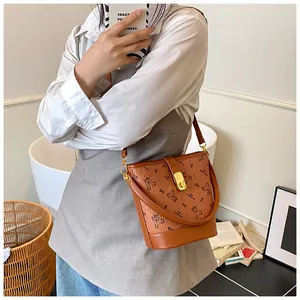 Détail du sac seau en cuir marron avec imprimé ours et fermoir doré