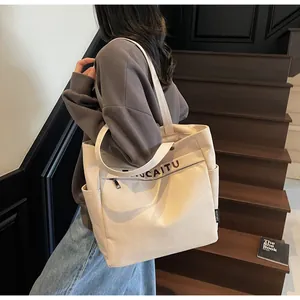Dettaglio della grande borsa tote in tela con stampa di lettere e tasche su scala in legno