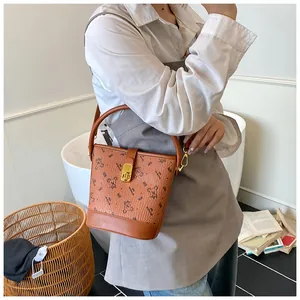 Gros plan sur un sac seau marron avec imprimé ours et fermoir métallique doré brillant