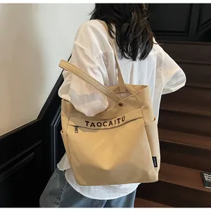 Dettaglio borsa tote in tela beige con stampa di lettere e tasche laterali per il pendolarismo